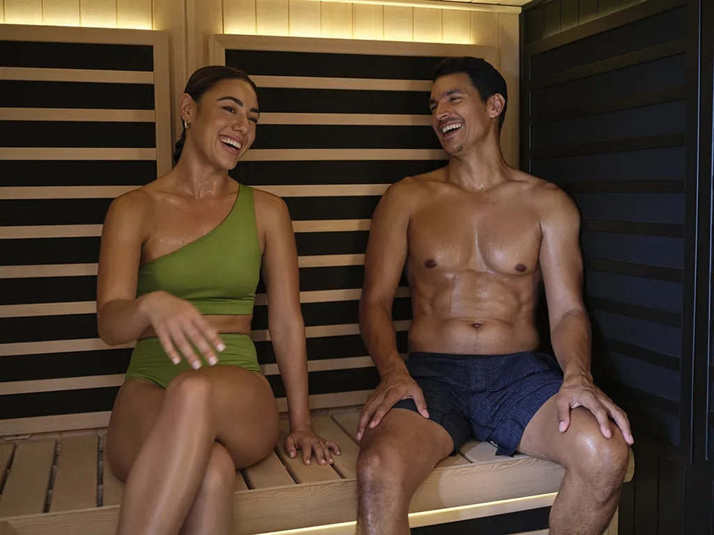 This is a lifestyle image showing two people sitting next to each other in the sauna.