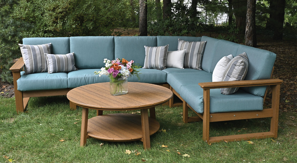 This is a lifestyle image showing the deep seating sectional set in a grassy backyard. The frames are antique mahogany and the cushions are cast breeze.
