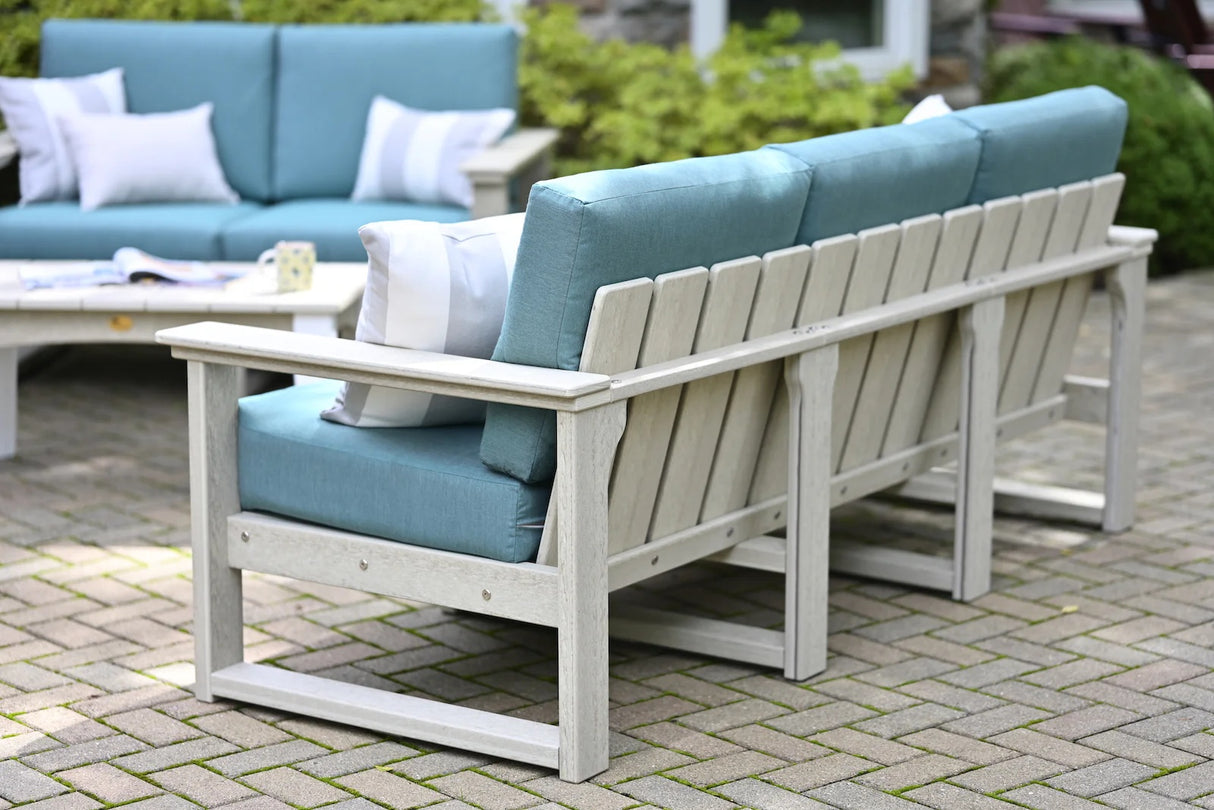 This is a lifestyle image showing what this deep seating sofa looks like from the back. The sofa is on a brick patio. The frames are dove gray and the cushions are cast breeze.