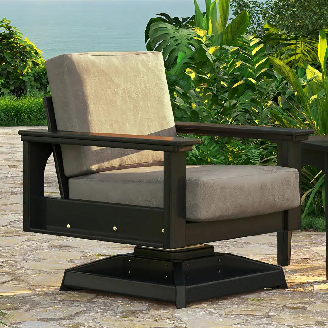 This is a lifestyle image showing the deep seating swivel rocker chair on a stone patio on a sunny day. The frames are black and the cushions are spectrum dove.
