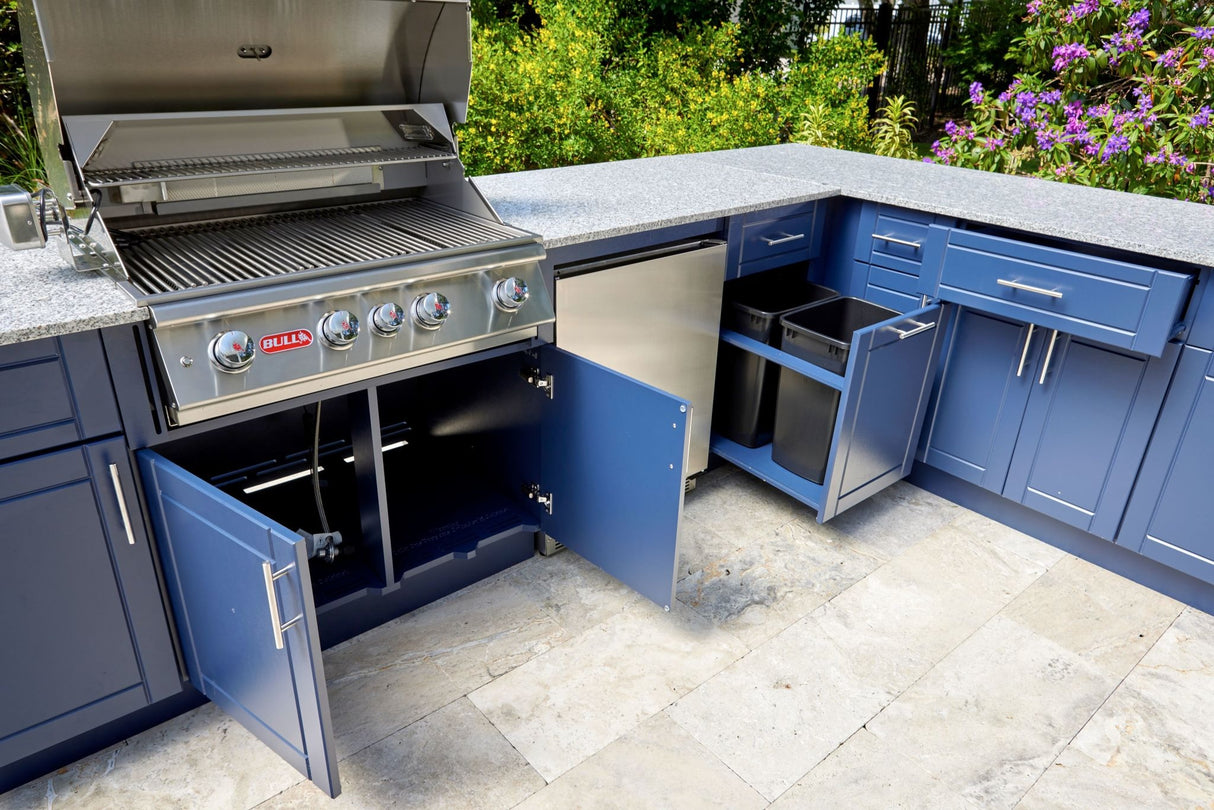 Bull outdoor kitchen. The base is Symphony Blue and the granite top is Galaxy White. Some of the cabinets are open so you can see the space inside. The cabinet for the trash reveals two trash cans inside.