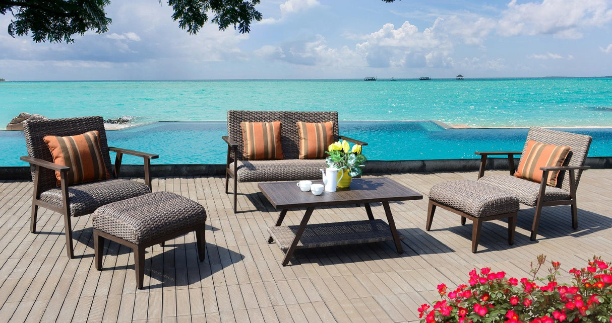 This is a lifestyle image showing this patio set on a wooden dock next to an infinity pool. The ocean is visible in the background, along with a few boats in the distance.