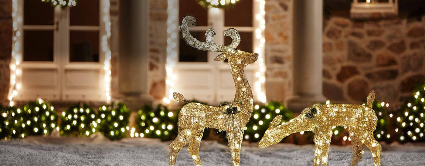 Outdoor lighted buck and deer Christmas decorations in a snowy yard.