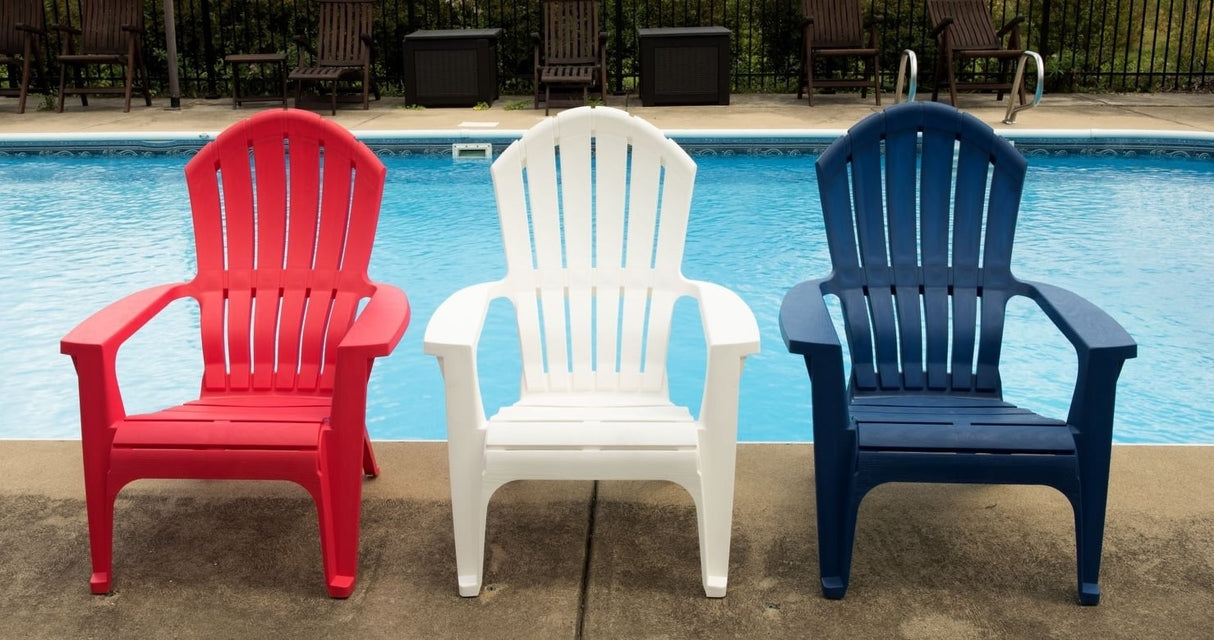 Red, white and blue Adirondack chairs near a pool.