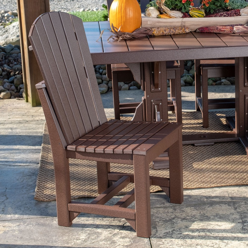 This is a lifestyle image showing the Chestnut Brown colored Adirondack Side Chair next to a matching patio dining table on a stone patio.