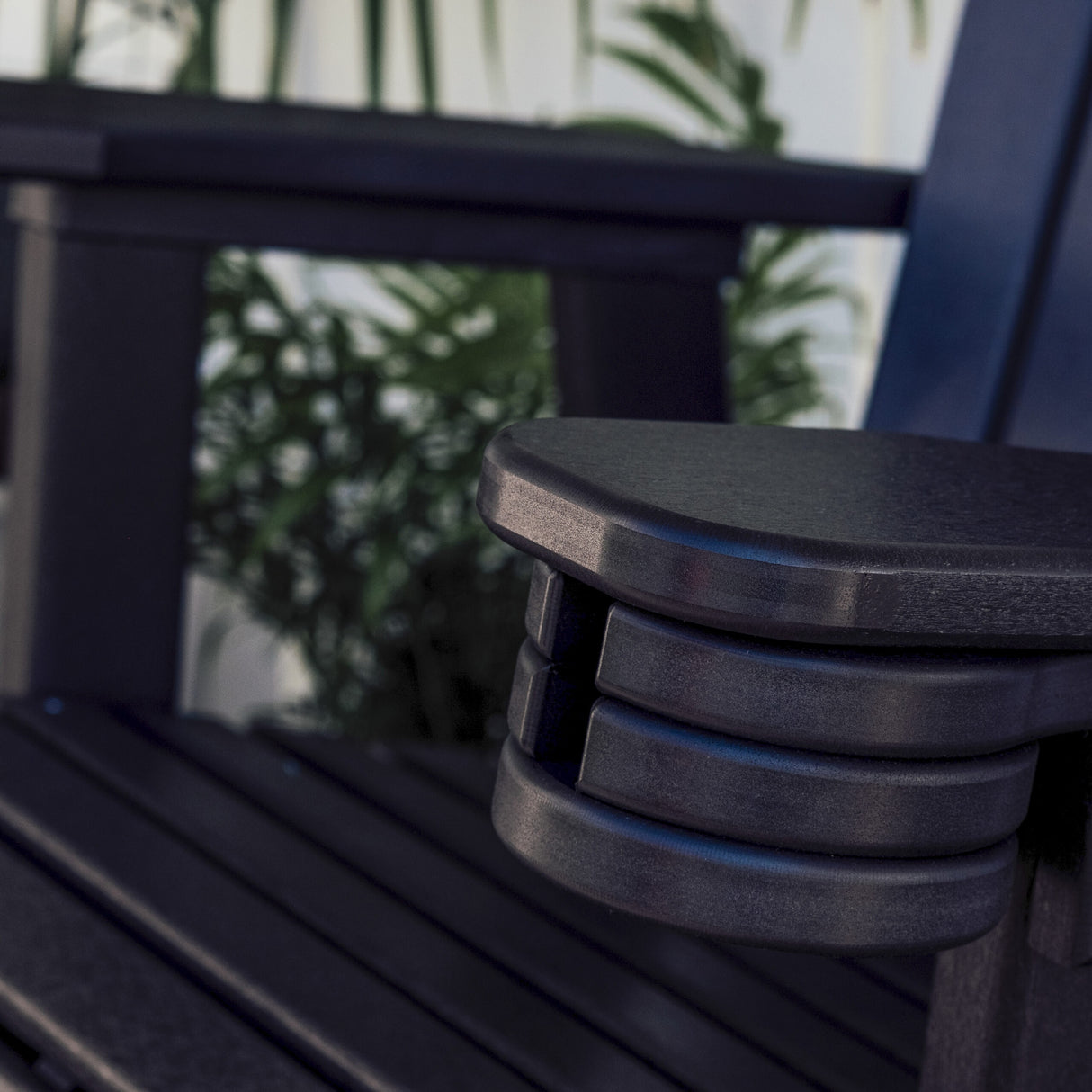 This is a lifestyle image showing the Black cup holder slid under the armrest of a black colored chair.