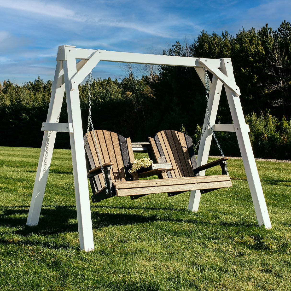 This is a lifestyle image showing the white A-frame vinyl swing stand with an Antique Mahogany and Black colored bench.