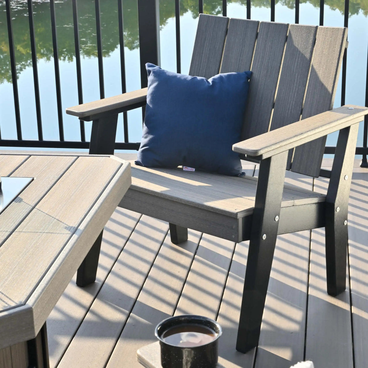 This is a lifestyle image showing the Coastal Gray and Black colored chat chair on a balcony overlooking a small body of water.