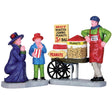 Village accent for a Lemax display. Designed to look like a peanut vendor leaning up against his cart. There's a mom excitedly watching her son eat peanuts.