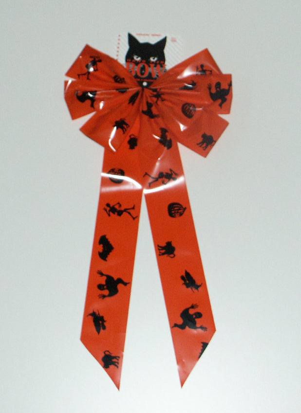 Orange bow with black figures on it. The figures include a skeleton, a pumpkin, a cat, a switch on a broom and a bat.