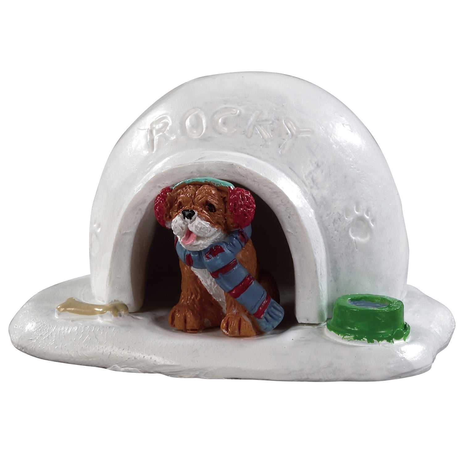 Polyresin figurine for a Lemax Village tabletop display. Designed to look like an igloo with a dog inside wearing earmuffs and a scarf. The name Rocky is written in the snow and there's a paw print on the side
