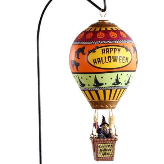 Polyresin carnival ride for a Lemax display. Designed to look like a hot air balloon with a lot of Halloween figures features on it. Things like pumpkins, witch hats and black cats. The colors on the hot air balloon are yellow, black, red, orange, light green and white. The basket underneath the balloon has a witch holding a broom.