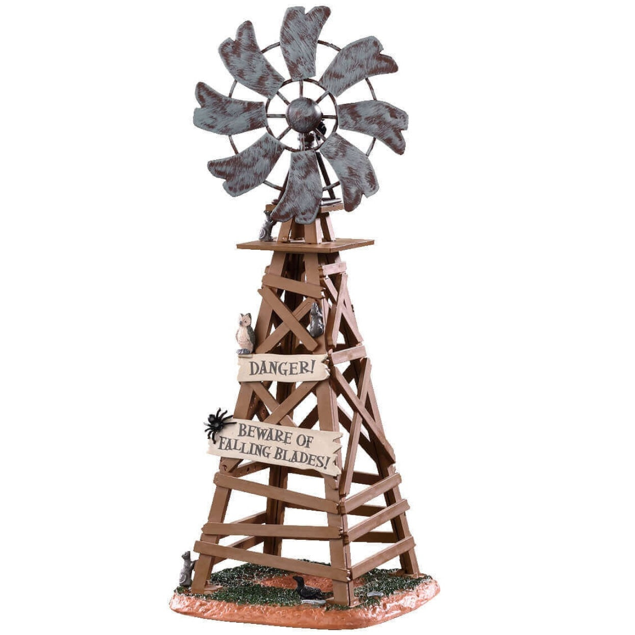 Polyresin table accent for a Lemax display. Designed to look like a wooden windmill with metal blades. There are two signs on it that read "DANGER!" and "BEWARE OF FALLING BLADES!" The danger sign has a small owl sitting on it. The beware sign has a big, black spider on it. There's a little bit of grass and dirt on the ground underneath it. There's a small rat standing at the bottom.