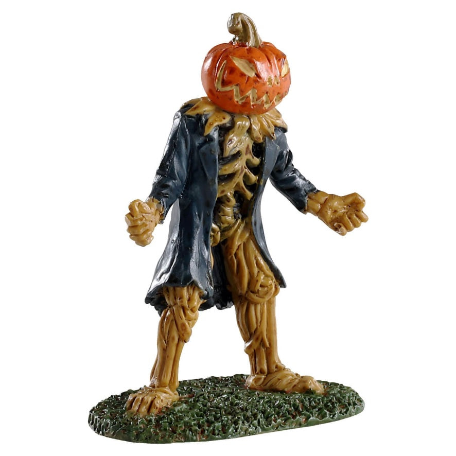 Polyresin figurine for a Lemax Spooky Town display. Designed to look like a pumpkin monster. It looks like the guts of the pumpkin have formed a skeleton and the pumpkin is the head. It's carved into a spooky smile. He's wearing a long blue jacket and standing on grass.