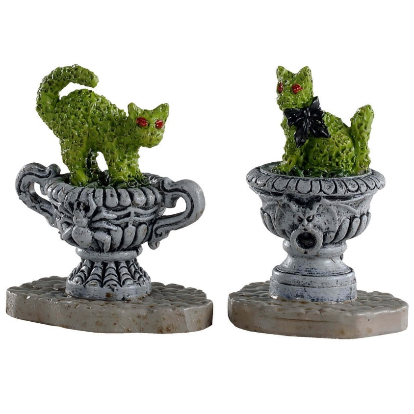 Polyresin village accents for a Lemax display. Designed to look like green bushes that have been trimmed to look like cats. One of the bushes is in a pot that has a spider on it. The other bush is in a pot that has a bat on it.