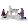 Polyresin figurines for a Lemax Village tabletop display. Designed to look like two kids petting a trio of husky dogs in the snow. They're wearing warm winter clothes