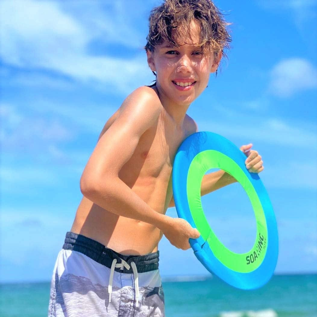 This picture shows a bow on a beach getting ready to throw the turquoise and neon green frisbee.