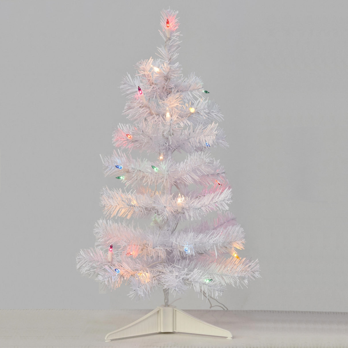 Small white tree pre-lit with multi-colored lights.