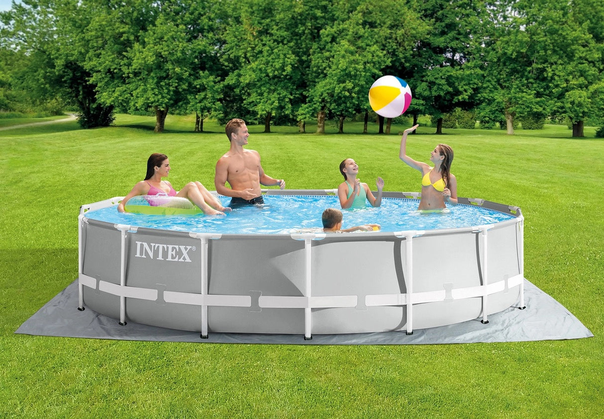 This is a lifestyle image showing a family inside the pool in a grassy backyard. The kids are playing with a beach ball and the mom is floating on an inner tube while dad overlooks the kids. The pool has a ground over underneath it.