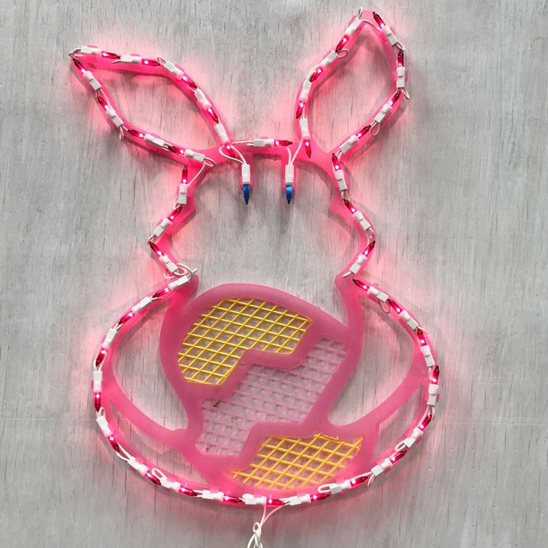 A pink window silhouette decoration shaped like a bunny holding a yellow egg