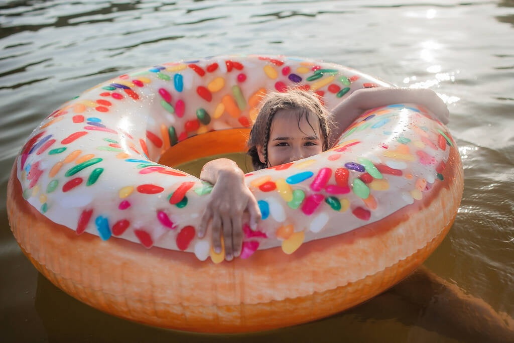 Inflatable inner tube designed to look like a donut with frosting and multi-colored sprinkles.