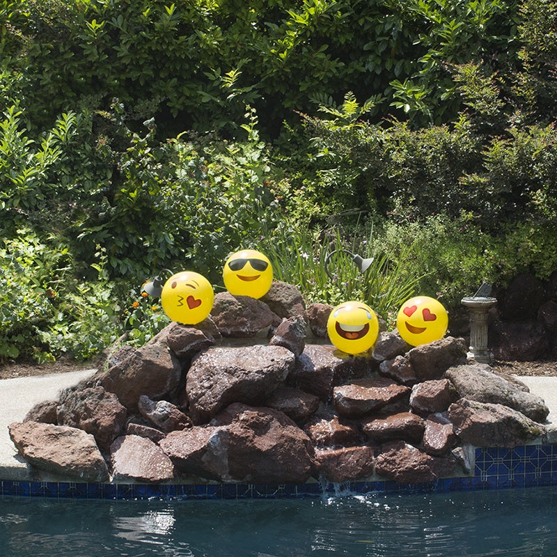 Yellow beach balls designed to look like different emojis.
