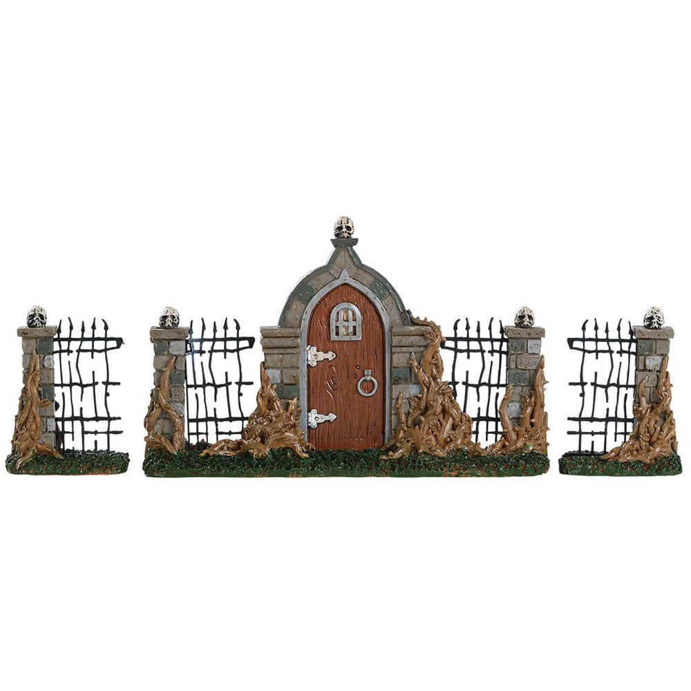 Polyresin village accent for a Lemax display. Designed to look like a run down, black metal fence with stone columns. There's a wooden door with stone around it. There's a skull on the top of the door and all the columns are covered in brown vines.