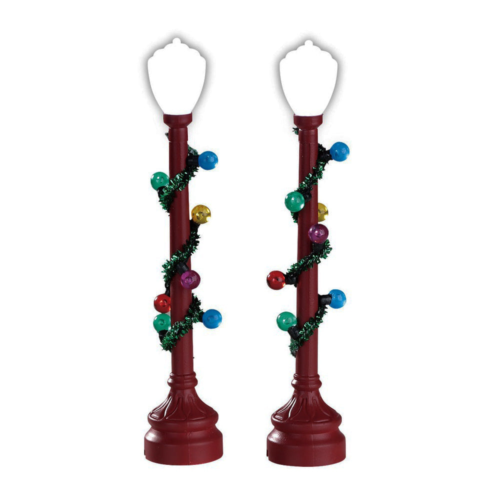 Lemax village accessories designed to look like red lampposts that have been decorated with green tinsel and multi-colored baubles. This is a set of two.