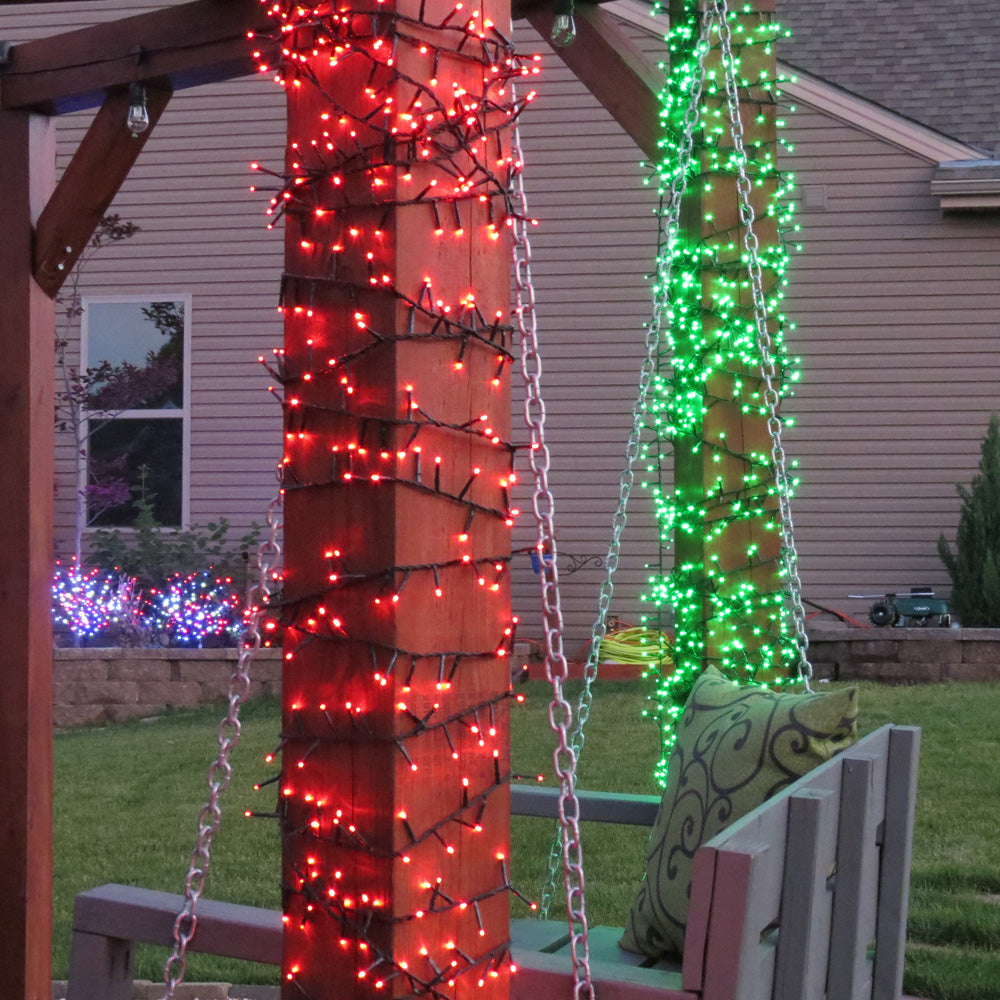 Rice lights on columns on a porch. One is a set of red lights and the other is green.