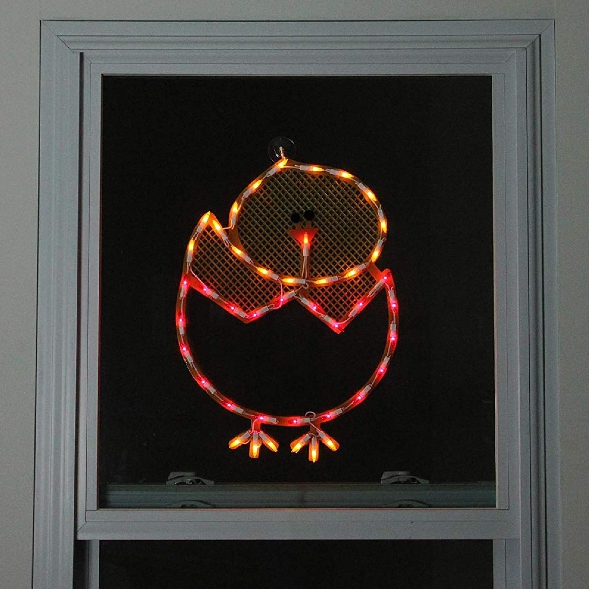 A window silhouette shaped like a chick in an egg. The colors are yellow, red and orange
