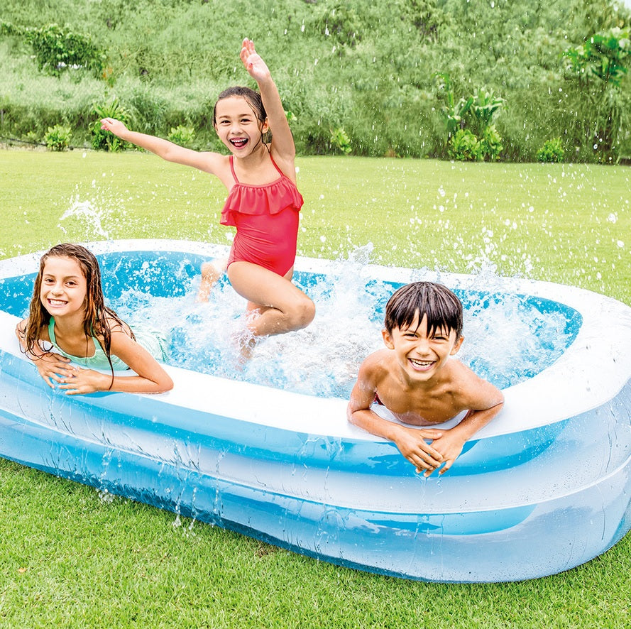 Children playing in an inflatable swimming pool outdoors.