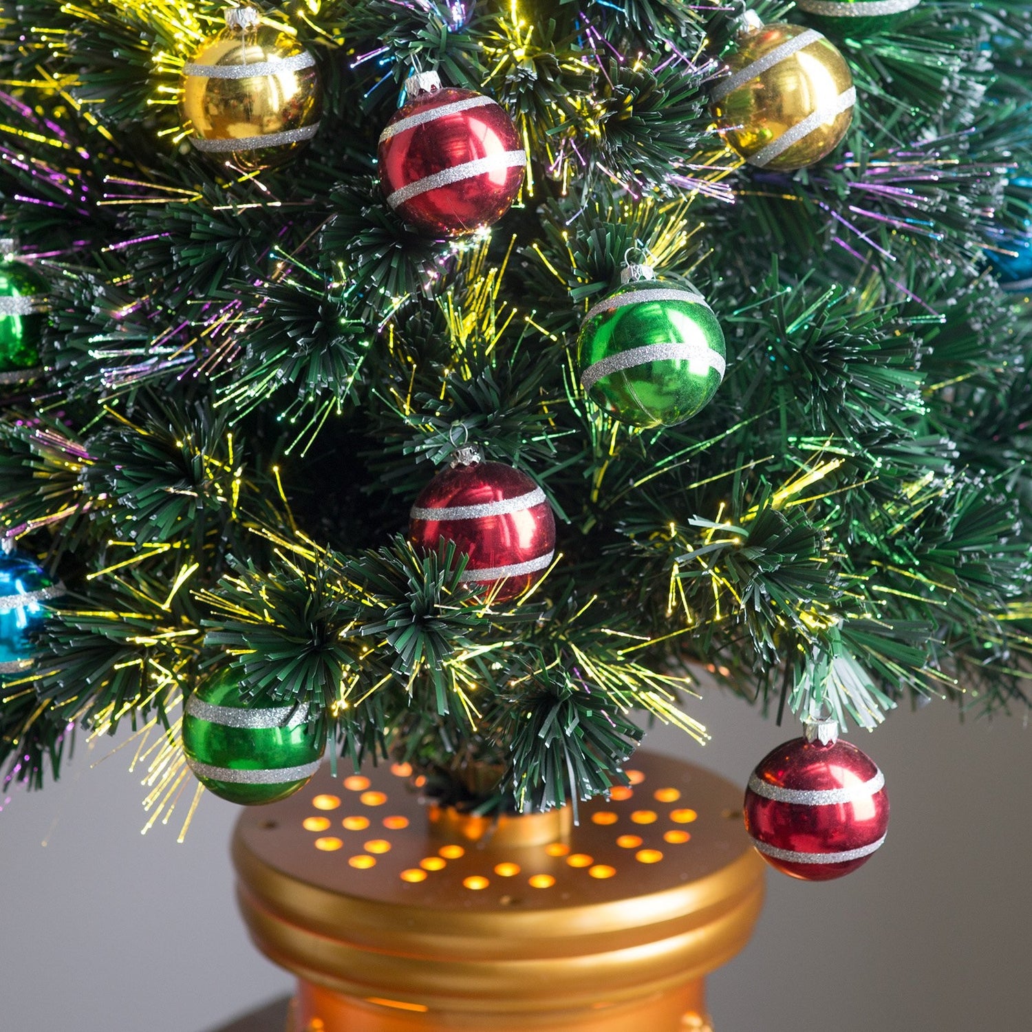 3 ft. fiber optic tree with multi-colored, glittered ball ornaments, a gold base and a star on top.