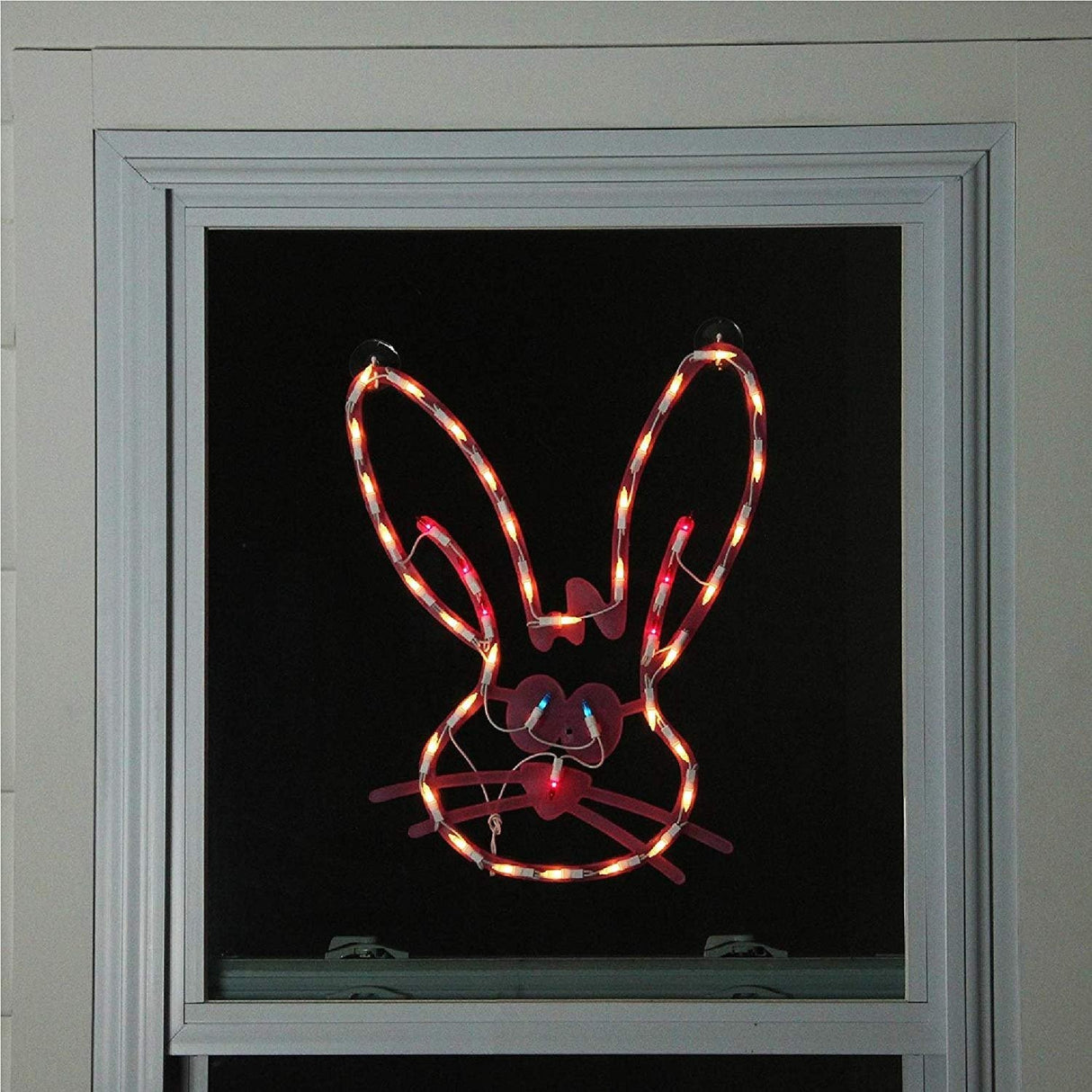 A pink window silhouette decoration for Easter. Designed to look like a cute bunny head with blue eyes and a red nose