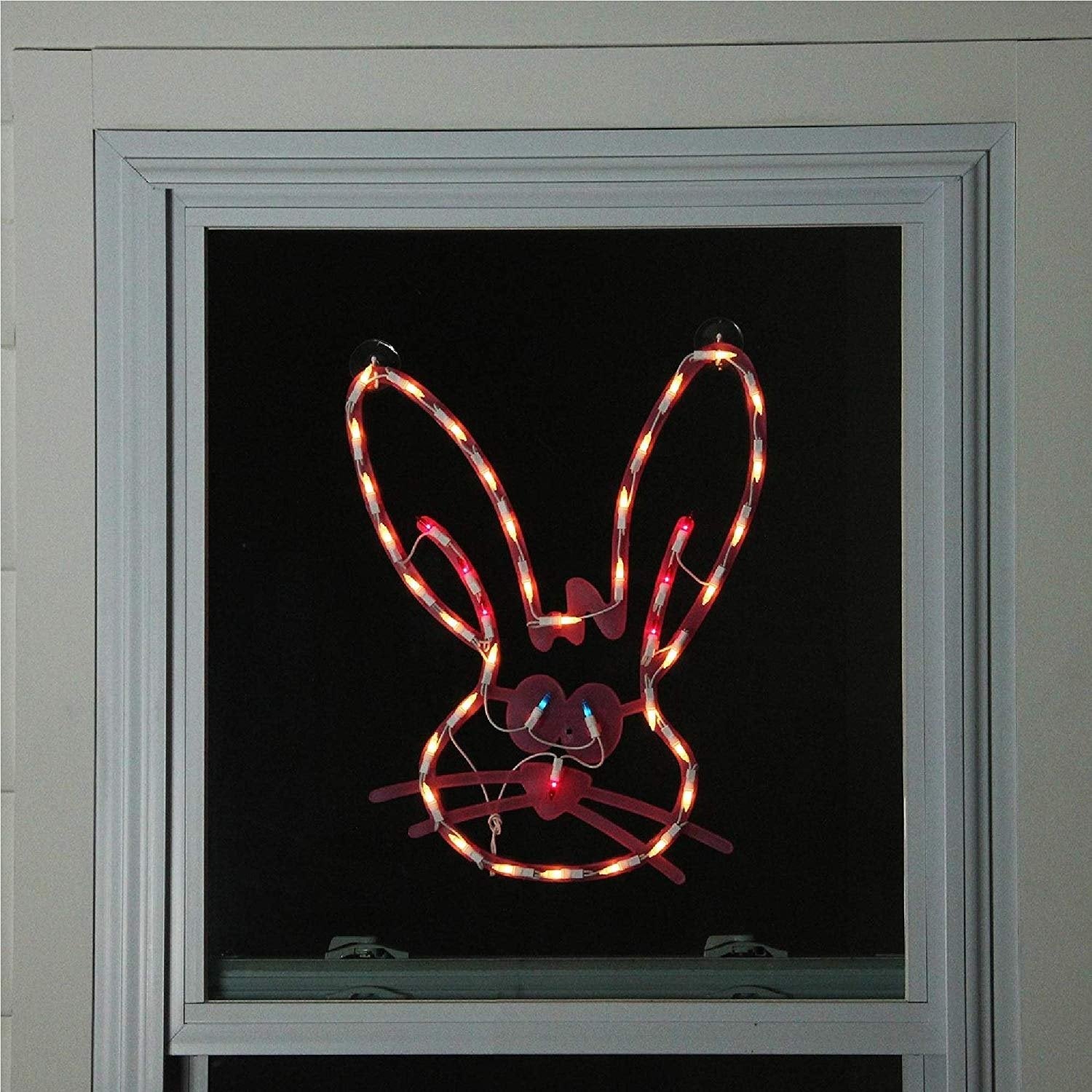 A pink window silhouette decoration for Easter. Designed to look like a cute bunny head with blue eyes and a red nose