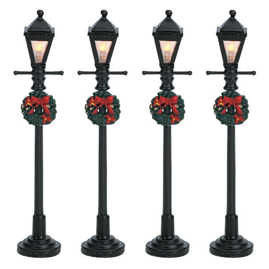 Set of 4 Lemax village lampposts. Each is decorated with a Christmas wreath.