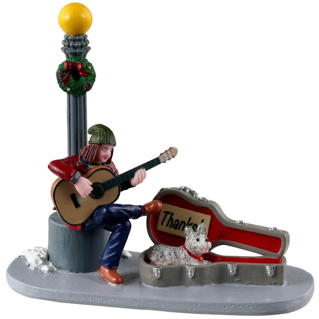 Resin figurine for a Lemax display. Designed to look like a woman sitting underneath a lamppost playing guitar for money. Her guitar case is open and there's a sign inside that reads "Thanks!" There's also a dog inside the guitar case. There's a bit of snow on the sidewalk and a decorated wreath on the lamppost.