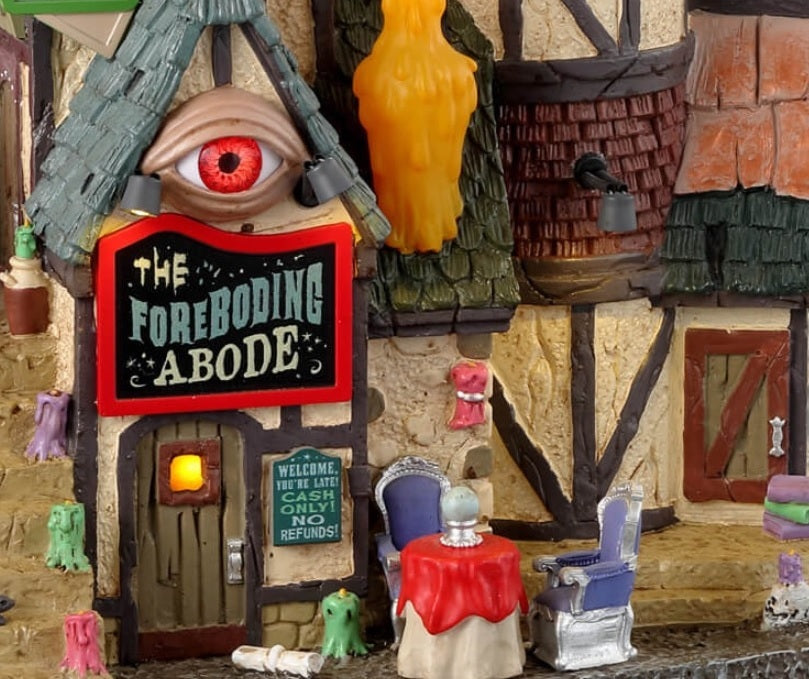 Resin lighted building for a Lemax display. Designed to look like an old-timey cottage. There are colorful candles everywhere. There's an eye above the front door and a giant crystal ball on the roof with a skull, an eye, a broken heart and a moon inside. There's a table outside with two chairs and a crystal ball on the table.