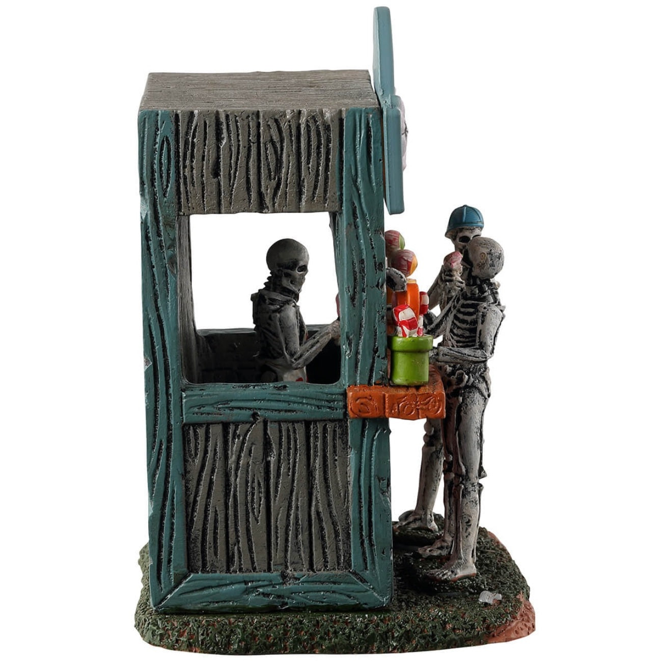 Resin village table accent for a Spooky Town Lemax display. Designed to look like a wooden candy stand. There's a skeleton serving candy to two young skeleton children. There are pots of candy on the side and pots of eyeballs on the other.