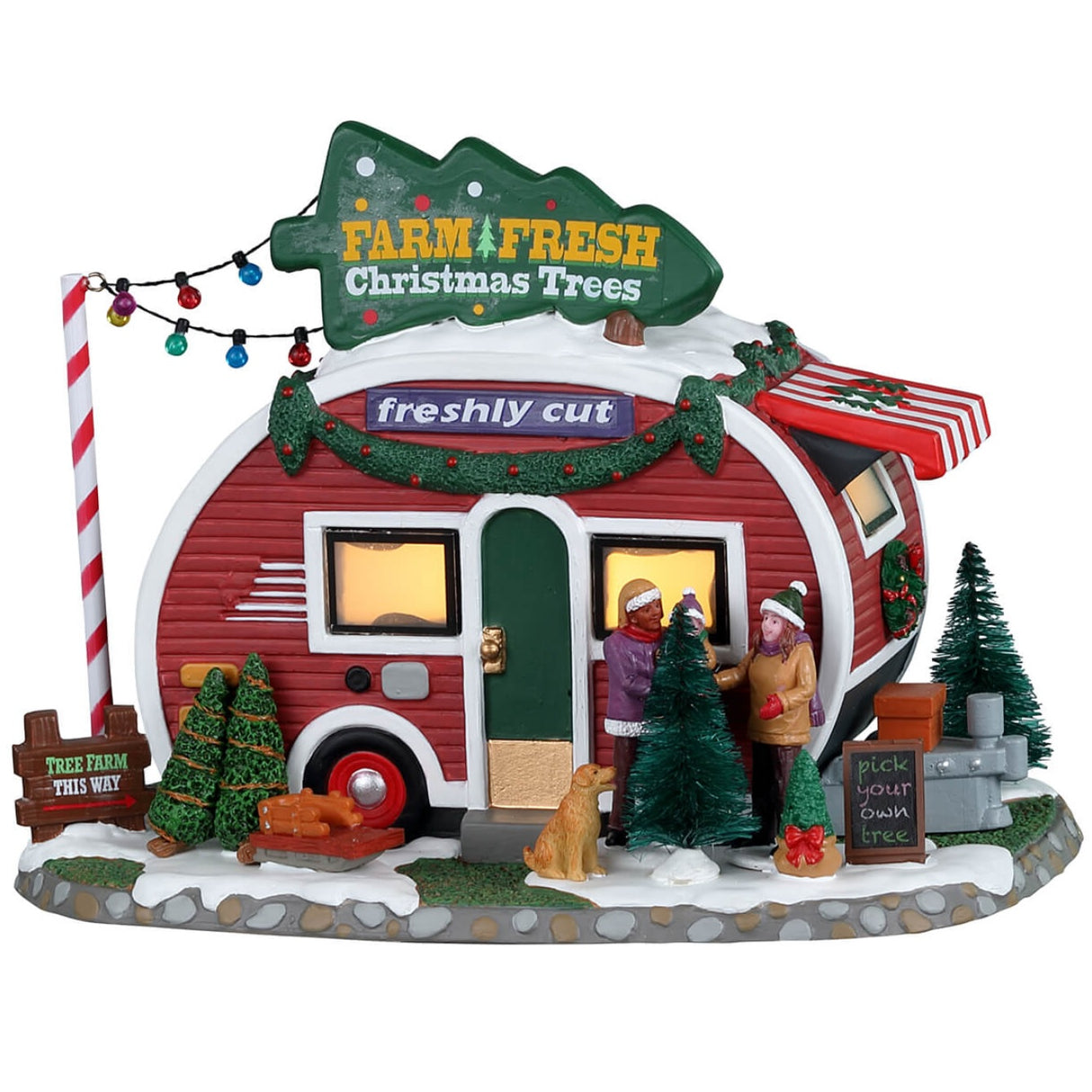 Porcelain lighted building for a Lemax display. Designed to look like a small red and white camper that's selling fresh Christmas trees. There are two people and a puppy checking out some of the trees outside.