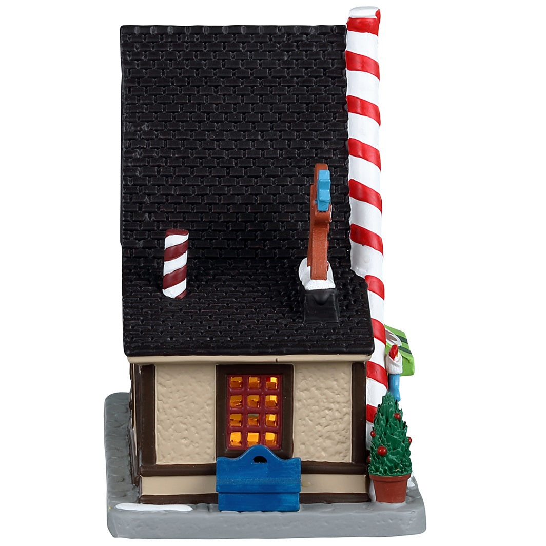 Porcelain lighted building for a Lemax display. Designed to look like an A-frame candy shop. There's a large gingerbread cookie statue on the left and a bunch of large cookie and candy cane statues on the right side. There are potted plants and gumball machine accents.
