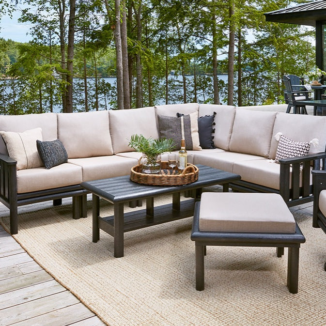 A resin patio furniture collection on a porch near a body of water