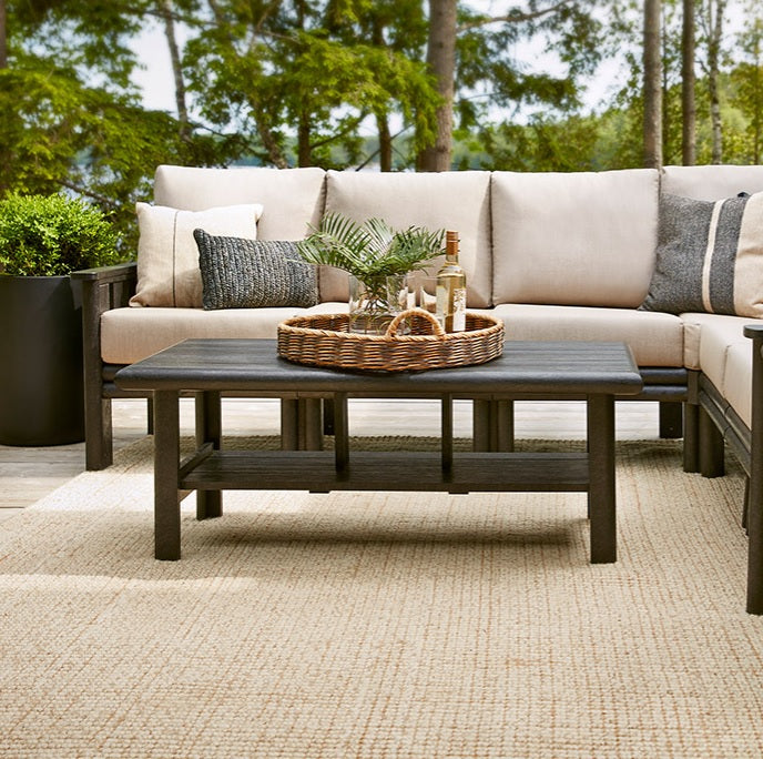 An outdoor sectional couch on a porch surrounded by trees