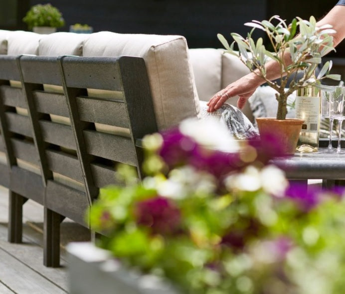 A close up of someone fixing the cushion on this outdoor couch