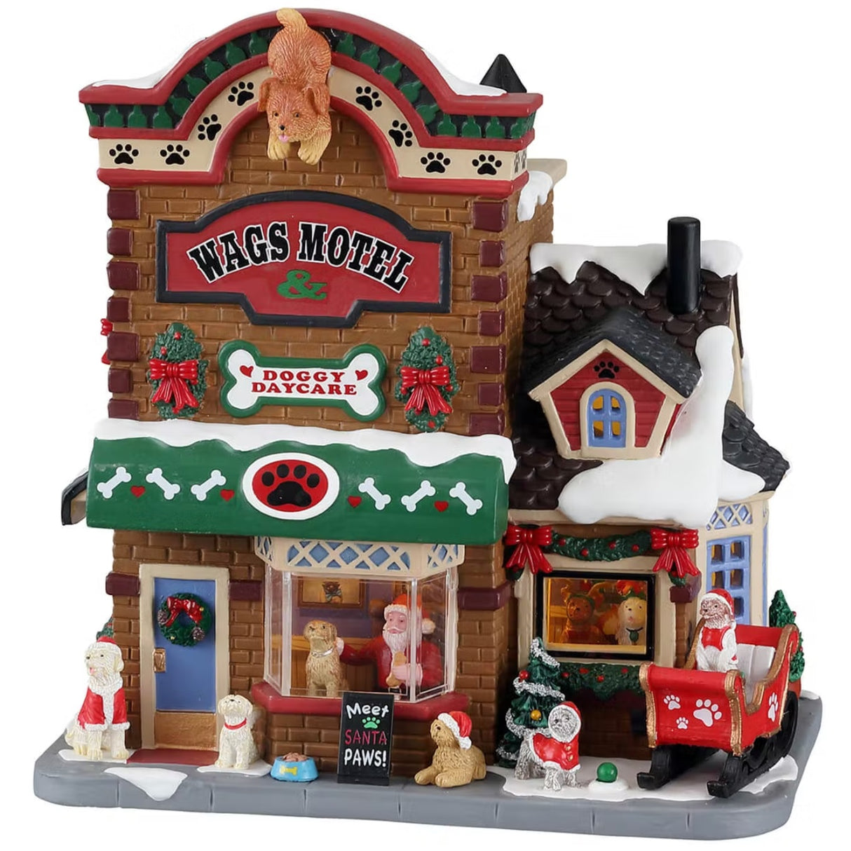 A porcelain lighted building for a Lemax display. Designed to look like a stone motel. There's a fake dog on the roof and a sign that reads "Wags Motel & Doggy Daycare." There's snow on the roof and on the ground. The building is decorated for Christmas and Santa is taking pictures with a dog in the front window. There are dogs wearing Santa hats and a dog in a red sleigh off to the side.