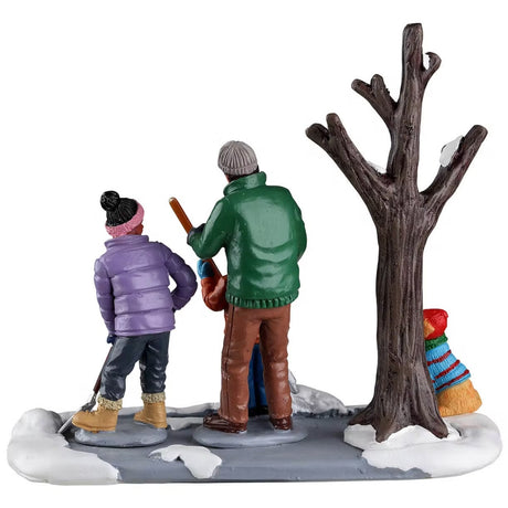 Resin table accent for a Lemax display. Designed to look like a dad and two of his young children shoveling snow away from a tree. There's a yellow dog wearing a sweater and a hat.