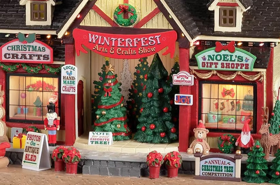 Resin lighted building for a Lemax display. Designed to look like an arts and crafts venue decorated for Christmas. There are decorated Christmas trees on stage for you to vote for your favorite. There's a Christmas crafts shop and a gift shop. There are poinsettia, sleighs, presents, a snowman, a teddy bear, an elf and a reindeer.