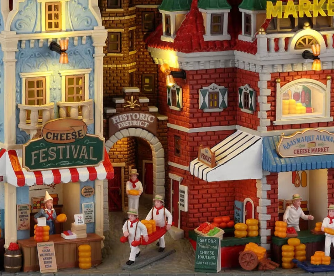 Resin lighted building facade for a Lemax display. Designed to look like a bunch of different store fronts in a public farmer's market. There's a cheese shop, a historic district and a cheese market.