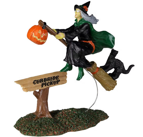 Polyresin figurine for a Lemax Spooky Town display. Designed to look like a witch riding a broomstick with a jack-o-lantern and a black cat on it. There's a sign on the ground that reads "CURBSIDE PICKUP." She's wearing a black robe, a green robe, green shoes and a black witch hat.