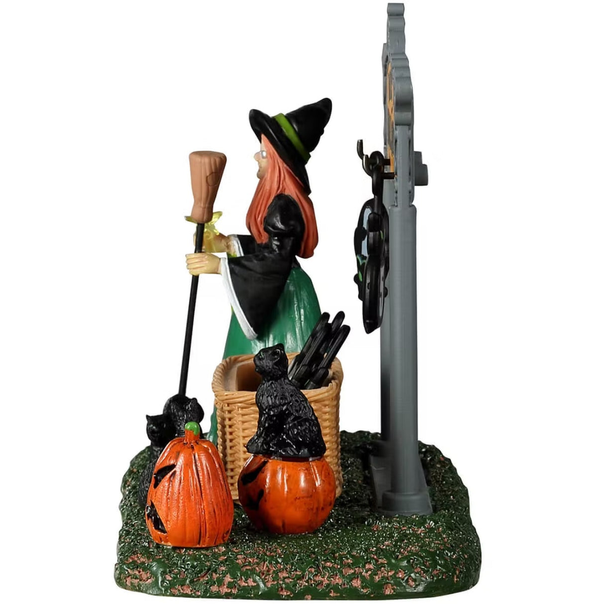 Resin village accent for a Spooky Town Lemax display. Designed to look like a witch holding a broom and a wand standing next to a Halloween countdown. The sign reads "Days 'Til Halloween" and there are removable numbers hanging off of it. There's a basket on the grass holding all the other numbers. There are black cats and jack-o-lantern accents. The number of days in this image are 24 days until Halloween.