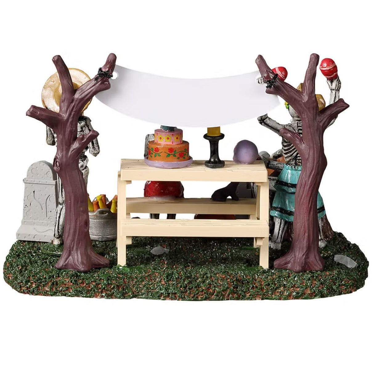 Resin village accent for a Spooky Town Lemax display. Designed to look like four skeletons enjoying a Day of the Dead celebration. There are tombstones, carved pumpkins and a banner hanging from the trees. There's a picnic table with a skull, a candle, a decorated cake and a rat on it.